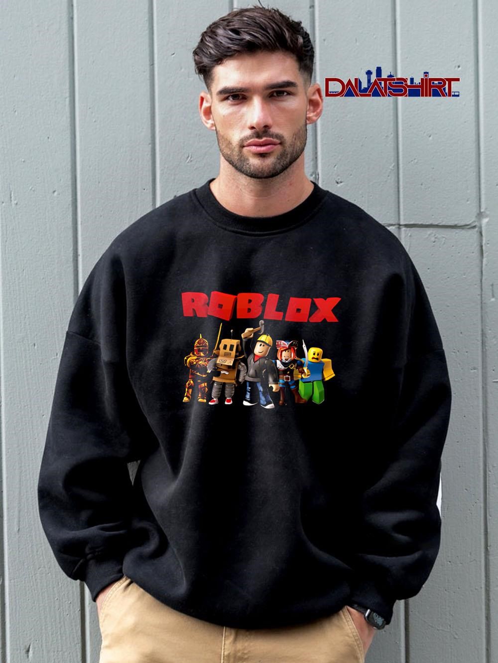 Man wearing a black Roblox crewneck sweatshirt with a red Roblox logo and character lineup